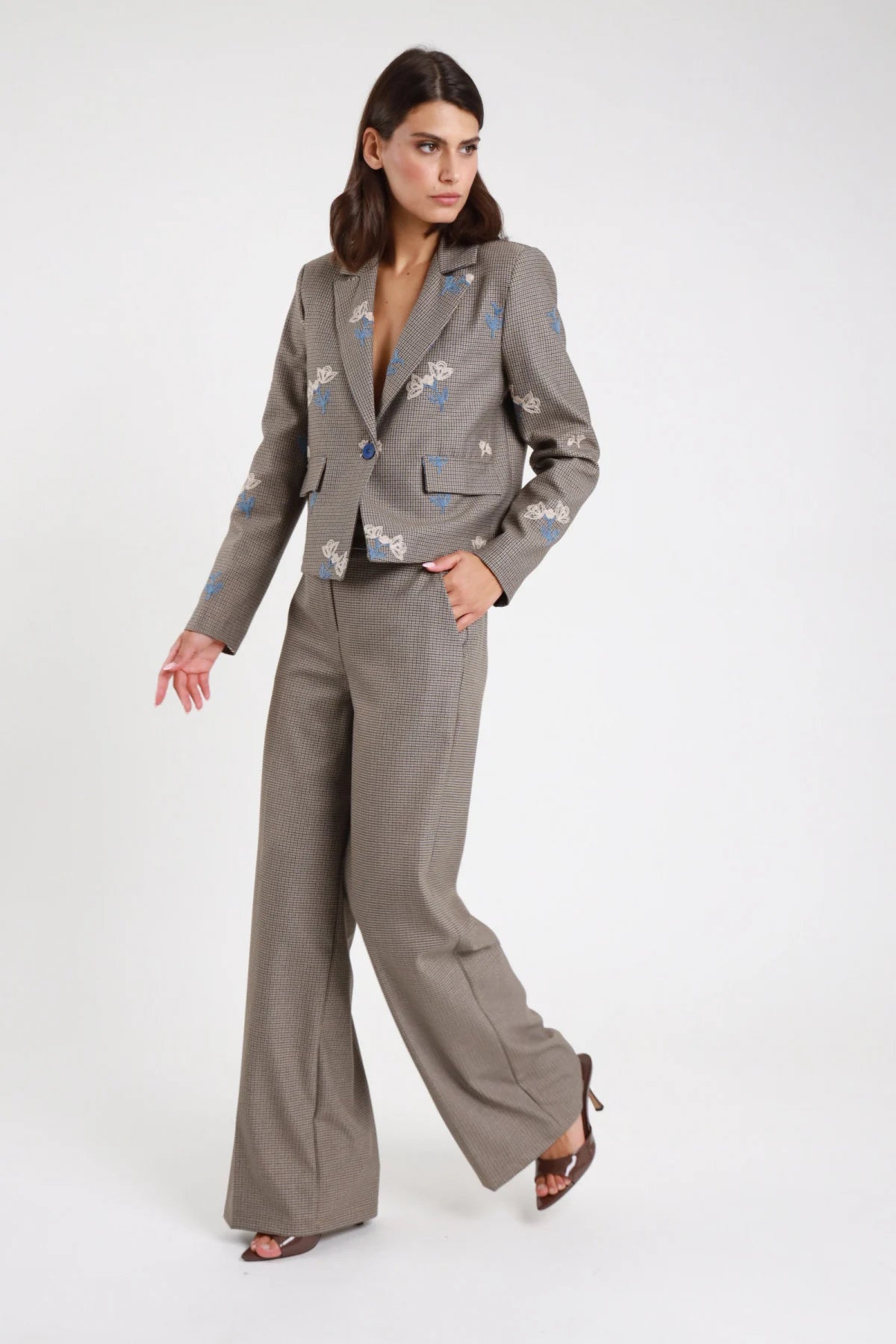 Pantaloni check palazzo wide-leg grigi - modella vista tre quarti con blazer check ricamato blu e décolleté