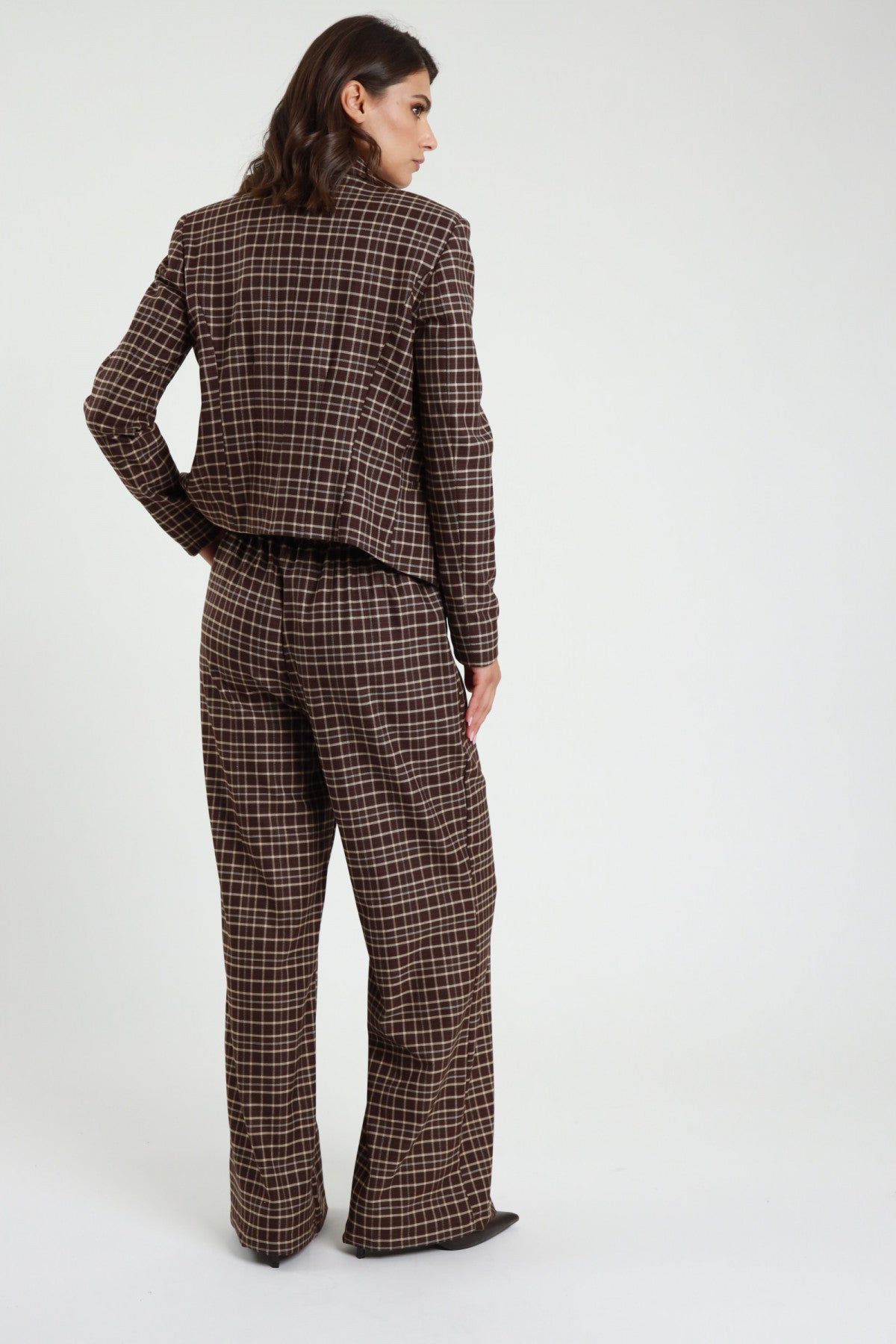 Pantalone Check tartan quadri marrone cioccolato wide leg palazzo maxi vita elastico retro intera con Blazer Check marrone - modella retro intera mano fianco sguardo laterale capelli castani scuri sfondo bianco blazer check marrone kitten heel neri
