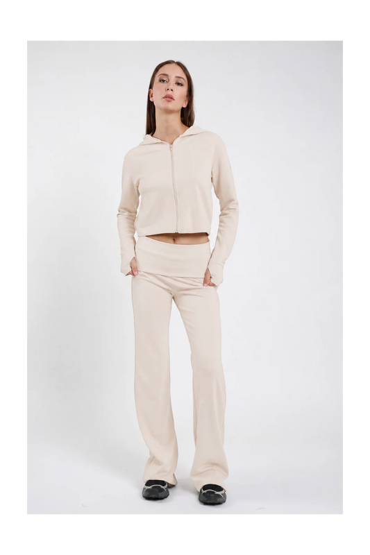 Pantaloni Flare DAYTHRU panna avorio elastico fold-over vita bassa logo SMX bianco coscia gamba flare bootcut silhouette scultorea frontale intera posa statica mani tasche sguardo frontale - modella frontale intera posa statica mani tasche sguardo frontale capelli castani lisci sfondo bianco felpa crop zip panna coordinata sabot neri