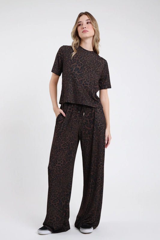 Pantalone animalier da donna a gamba ampia in stampa maculata scura, vista frontale indossato con top coordinato