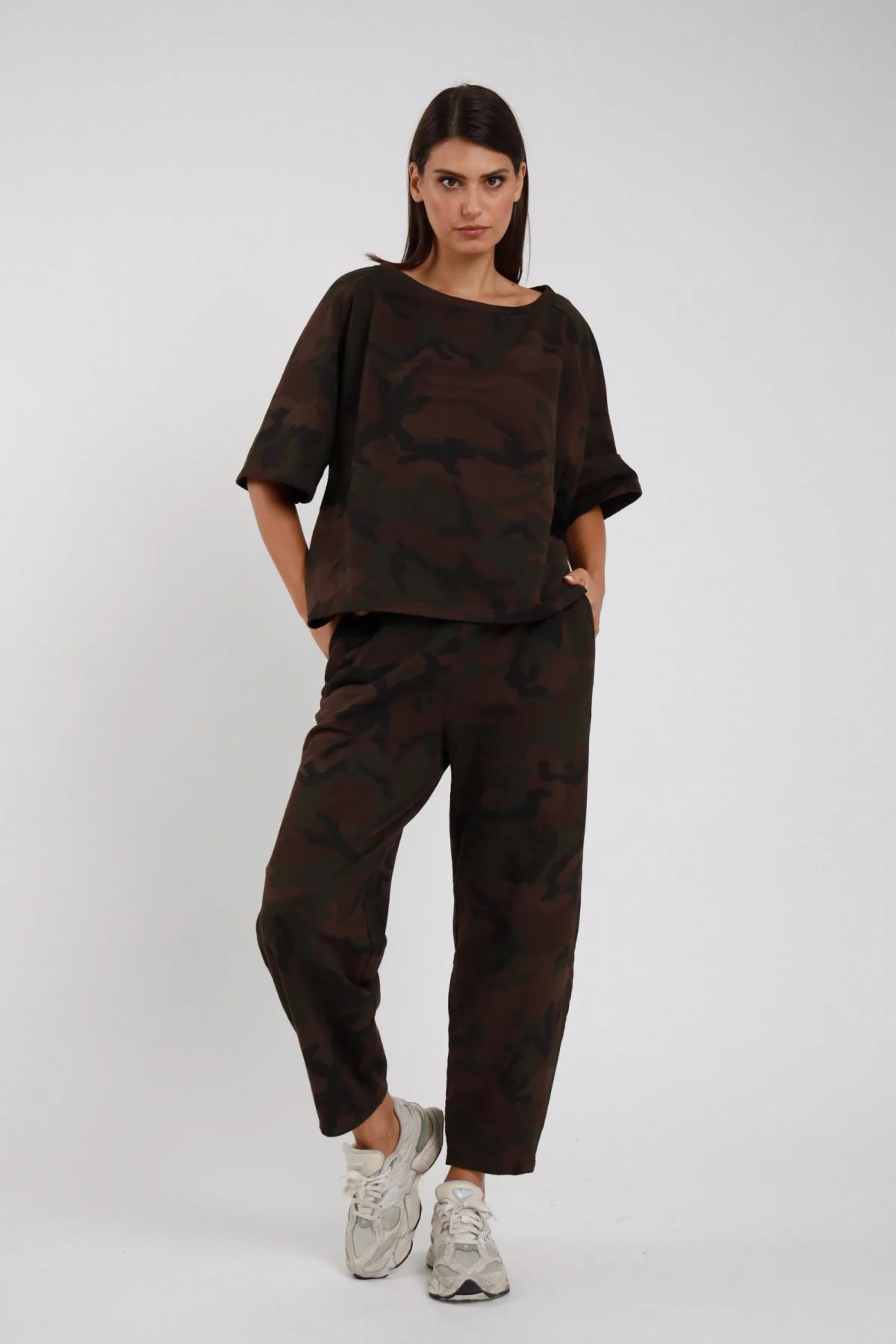 Pantalone Ovetto Mimetico camouflage marrone cioccolato nero sfumato 95% cotone vita alta elastico gamba balloon ovetto tasche laterali frontale intera posa statica mani tasche sguardo frontale - modella frontale intera posa statica mani tasche sguardo frontale capelli castani lisci sfondo bianco blusa oversize mimetica coordinata sneakers chunky beige