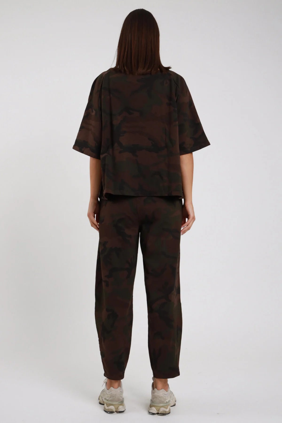 Pantalone Ovetto Mimetico camouflage marrone cioccolato nero sfumato 95% cotone vita alta elastico gamba balloon ovetto fondo arricciato caviglia posteriore intera posa statica mani fianchi - modella posteriore intera posa statica capelli castani lisci sfondo bianco blusa oversize mimetica coordinata sneakers chunky beige