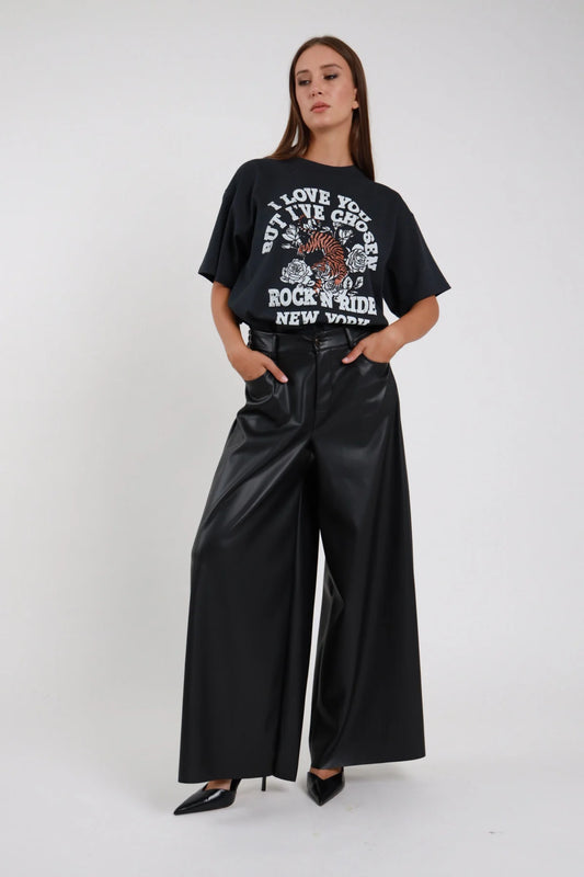 Pantalone palazzo ecopelle nero da donna a gamba ampia, indossato con t-shirt stampata, vista frontale