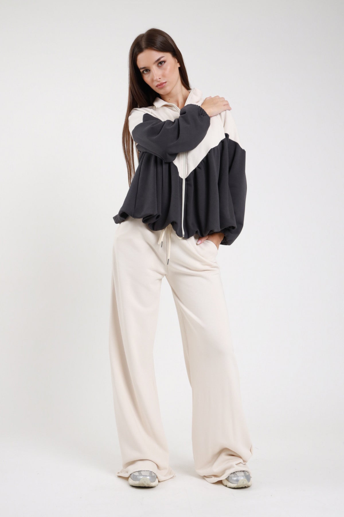 Pantalone felpa palazzo wide leg beige panna fascia elastica coulisse vita tasche gamba diritta full-length frontale intera - modella frontale intera mano spalla sguardo frontale capelli castani lisci sfondo bianco felpa bicolor bianco antracite sneakers argento
