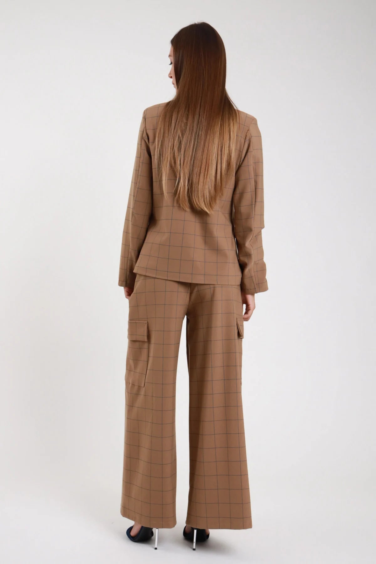 Pantalone quadri wide-leg palazzo cammello check retro intera secondo angolo - modella retro intera sguardo laterale giacca coordinata tacchi argento capelli castani lisci