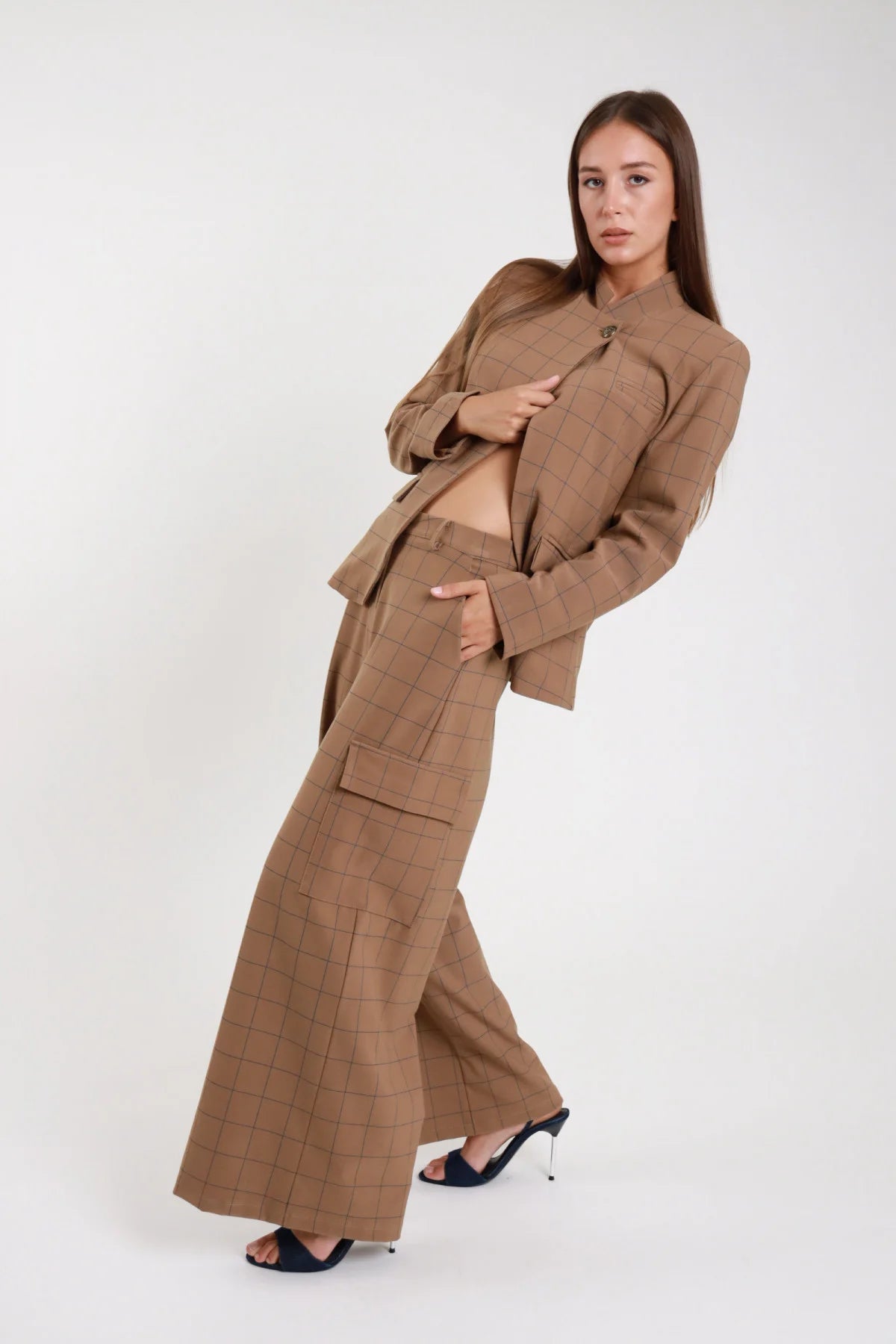 Pantalone quadri cargo cammello windowpane dinamico laterale intera - modella laterale intera pose dinamica braccia conserte giacca coordinata mules neri capelli castani lisci