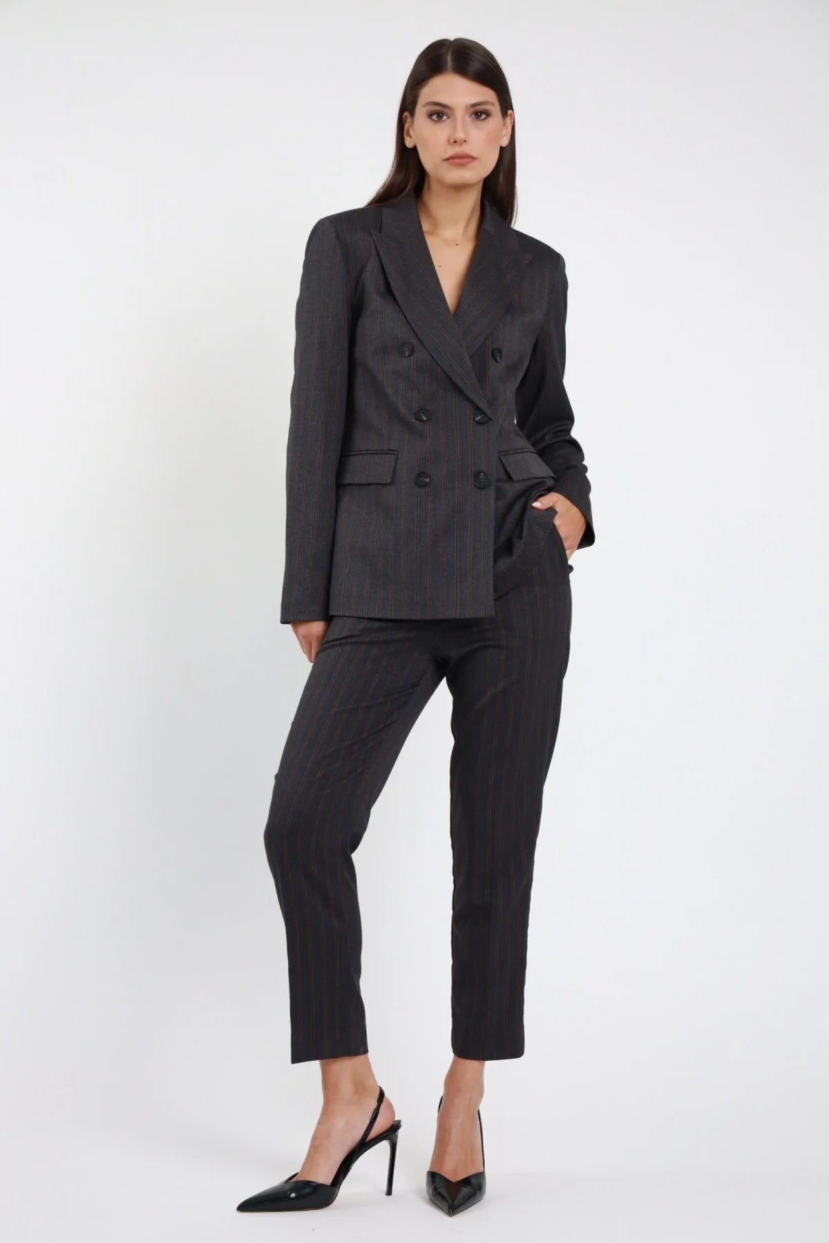 Pantalone slim gessato Susy Mix Pre-Fall grigio antracite pinstripe bordeaux ruggine 64% poliestere viscosa elastan vita alta gamba slim sigaretta affusolata caviglia frontale intera mano tasca sguardo frontale - modella intera frontale mano tasca sguardo frontale capelli scuri lisci sfondo bianco blazer doppiopetto gessato coordinato stesso tessuto tailleur slingback neri abbinati