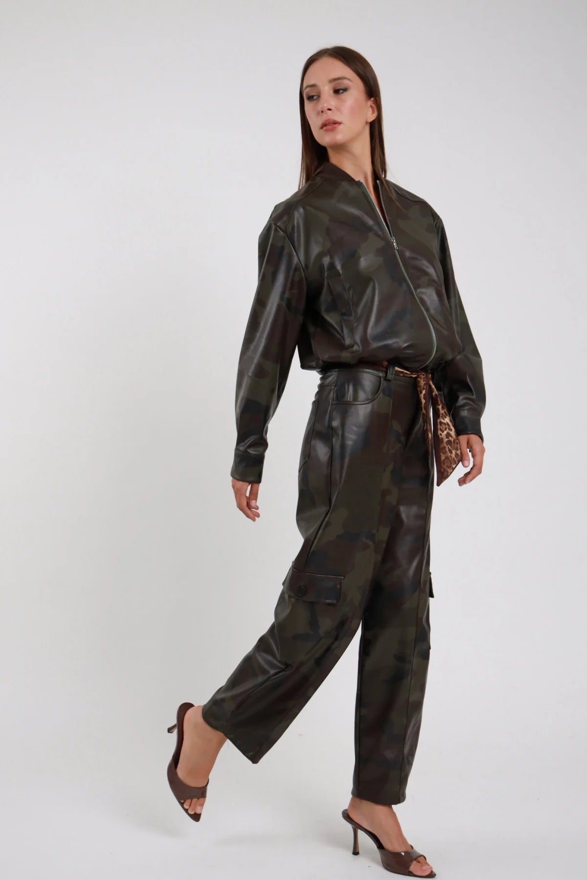 Pantalone Tasconi Mimetico cargo barrel ecopelle PU camouflage verde bronzo tasconi cargo zip decorativa vita media cintura leopardata frontale 3/4 posa laterale - modella frontale 3/4 posa laterale sguardo abbasso capelli castani lisci sfondo bianco bomber zip aperta coordinato mimetico mules tacco marrone