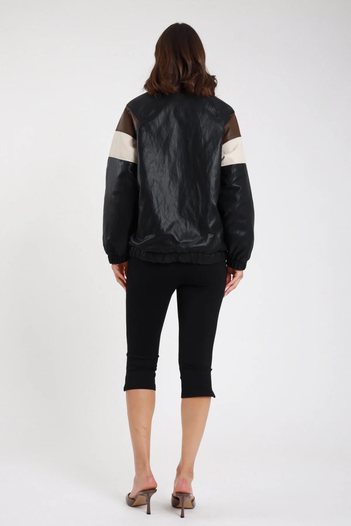 Pantaloni capri pinocchietto nero donna slim fit vita alta elasticizzata spacco laterale caviglie - vista posteriore intera con bomber ecopelle nero e sandali tacco marrone