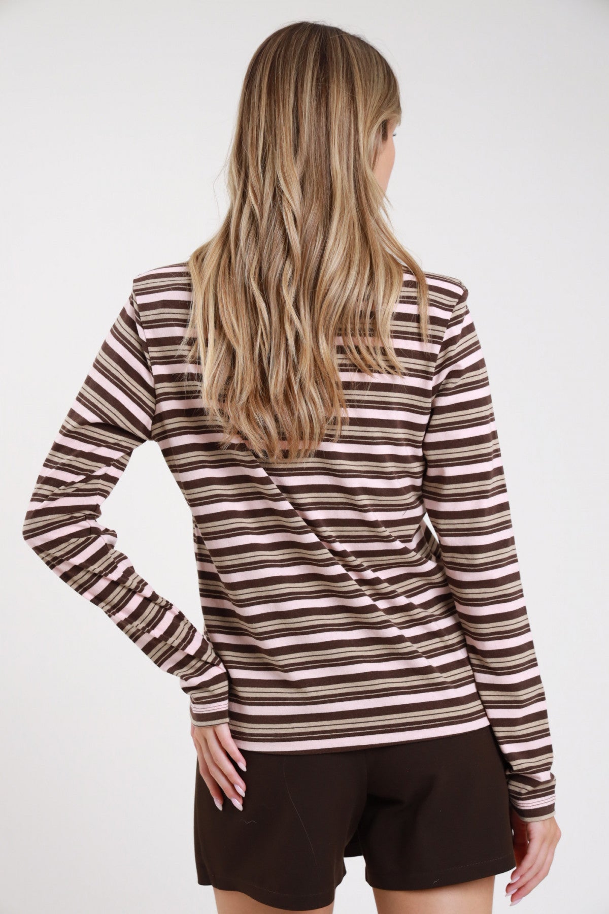Polo righe rosa cipria cioccolato caramello retro intera manica lunga polsino costina corpo oversize relaxed orlo dritto - modella retro intera mano fianco sguardo basso laterale shorts cioccolato capelli biondi onde