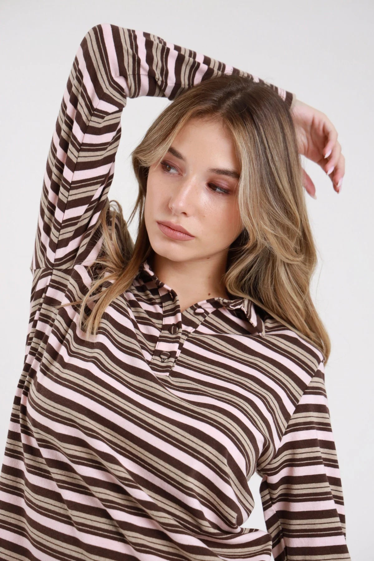 Polo righe rosa cipria cioccolato caramello frontale busto braccio alzato mano testa colletto polo righe multicolor melange oversize - modella frontale busto braccio alzato mano testa sguardo basso laterale gonna cioccolato capelli biondi onde
