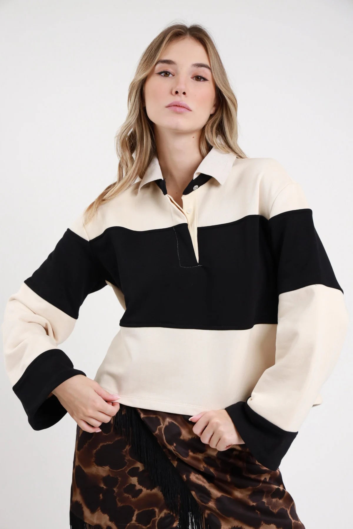 Polo Felpa Righe panna avorio nero 65% cotone righe maxi orizzontali color block colletto polo zip bottone dorato gioiello dettaglio fasce panna nero nette oversize boxy frontale busto mani fianchi - modella busto frontale mani fianchi sguardo frontale capelli biondi mossi sfondo bianco minigonna animalier frange abbinata