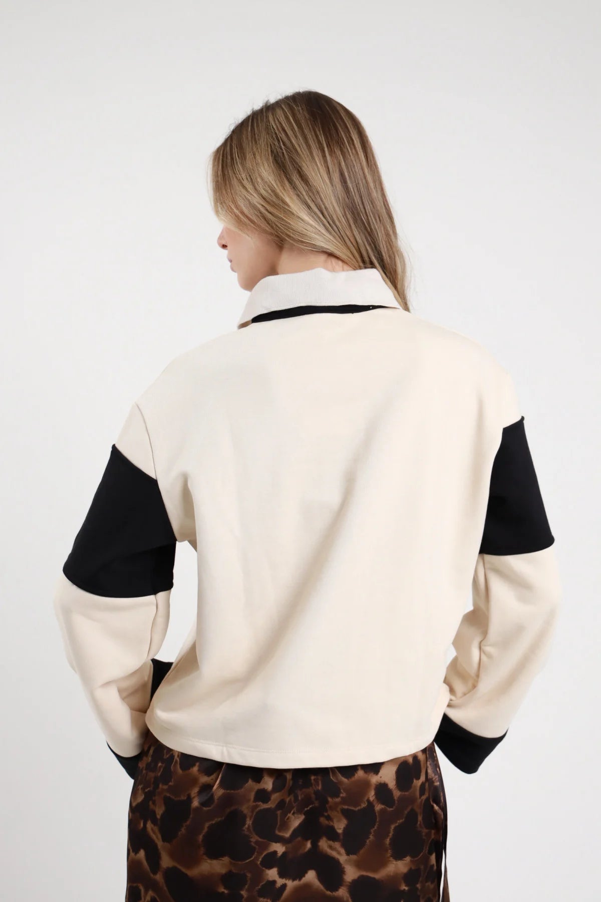 Polo Felpa Righe panna avorio nero 65% cotone righe maxi orizzontali color block fasce larghissime colletto polo zip bottone dorato gioiello manica lunga ampia fascia nera gomito polsino nero bordo fondo nero oversize boxy corta posteriore intera - modella intera posteriore capelli biondi lisci sfondo bianco minigonna animalier frange abbinata coordinata