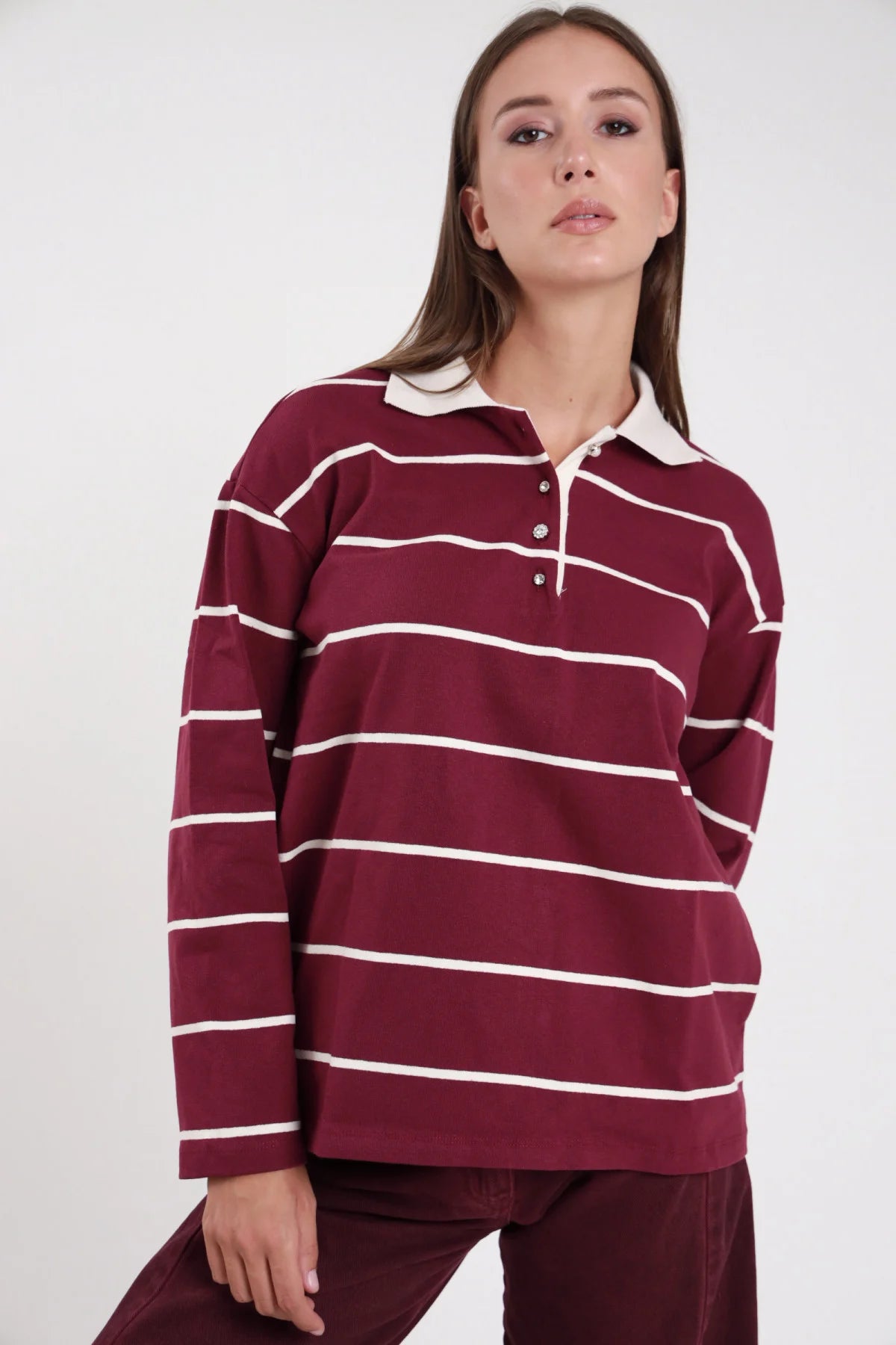 Polo righe rugby borgogna panna frontale intera colletto polo panna contrasto placchetta snap manica lunga boxy - modella frontale intera mano fianco sguardo frontale pantaloni bordeaux capelli castani lisci