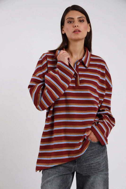 Polo Oversize Rugby Righe Multicolor bordeaux marrone cammello righe sottili blu elettrico bianco celeste 77% cotone colletto polo rovesciato ampio bottone collo manica ampia drop batwing silhouette maxi boxy fondo dritto asimmetrico frontale - modella busto 3/4 frontale posa mano colletto sguardo frontale intenso capelli castani lisci sfondo bianco jeans grigio antracite