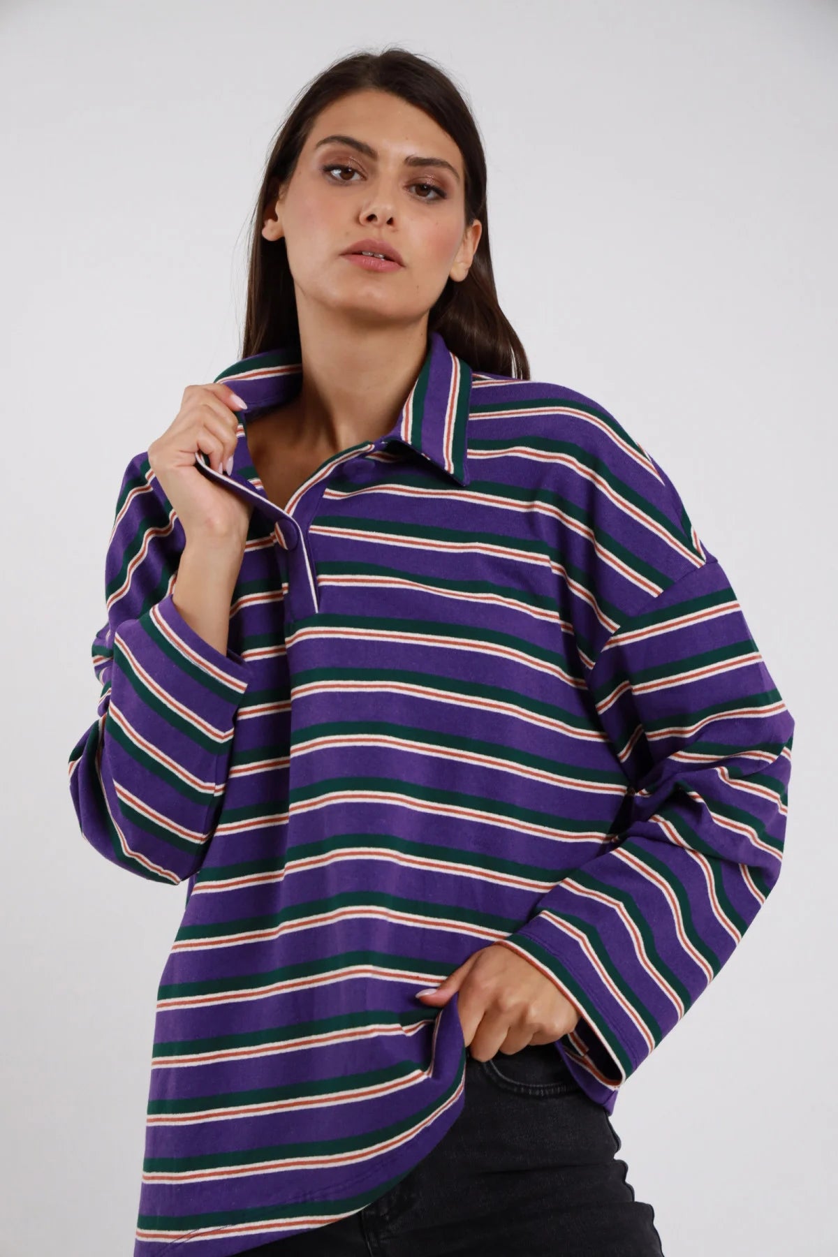 Polo Oversize Rugby Righe Multicolor viola intenso righe sottili verde bottiglia panna rosso arancio shimmer 77% cotone colletto polo rovesciato ampio bottone collo manica ampia drop batwing silhouette maxi boxy frontale - modella busto 3/4 frontale posa mano colletto sguardo frontale intenso capelli castani lisci sfondo bianco jeans nero