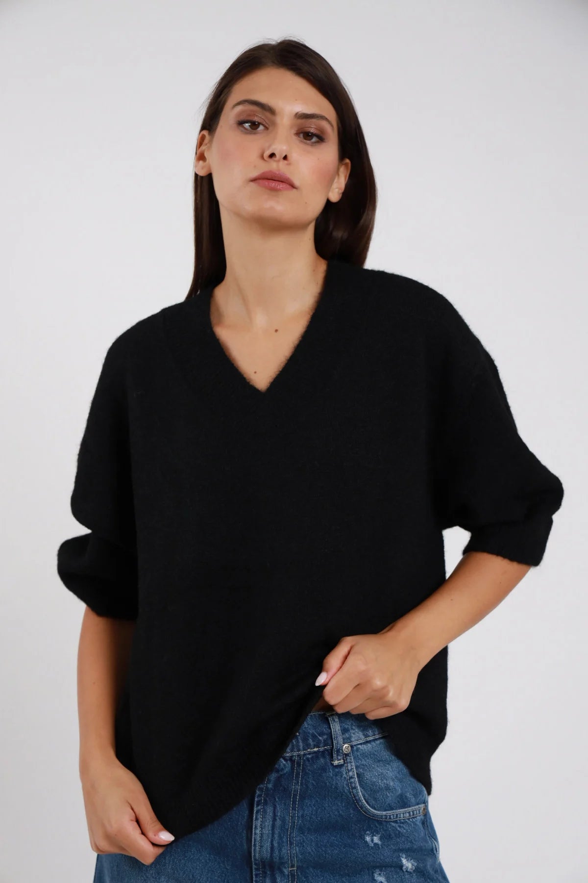 Pullover Scollo V nero maglia ultra morbida scollo V ampio manica 3/4 balloon risvolto orlo coste oversize boxy busto frontale 3/4 mano fianco sguardo frontale - modella busto frontale 3/4 mano fianco sguardo frontale capelli castani sfondo bianco jeans chiari