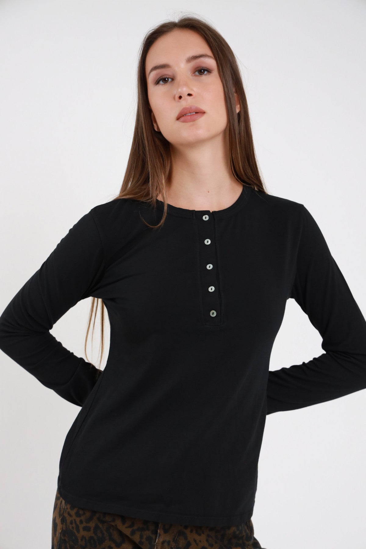 T-shirt serafino viola prugna donna maniche lunghe aderente bottoncini madreperla - vista frontale braccia conserte con pantaloni neri
