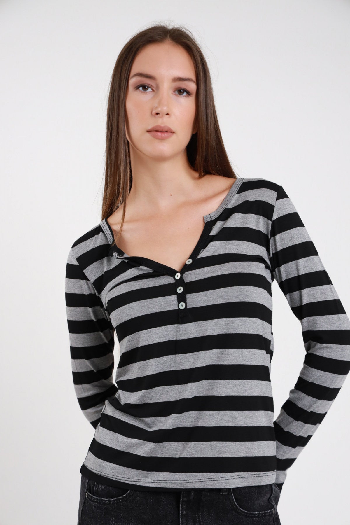 T-shirt serafino righe grigio nero donna maniche lunghe aderente bottoncini decorativi - vista frontale braccia conserte con jeans neri