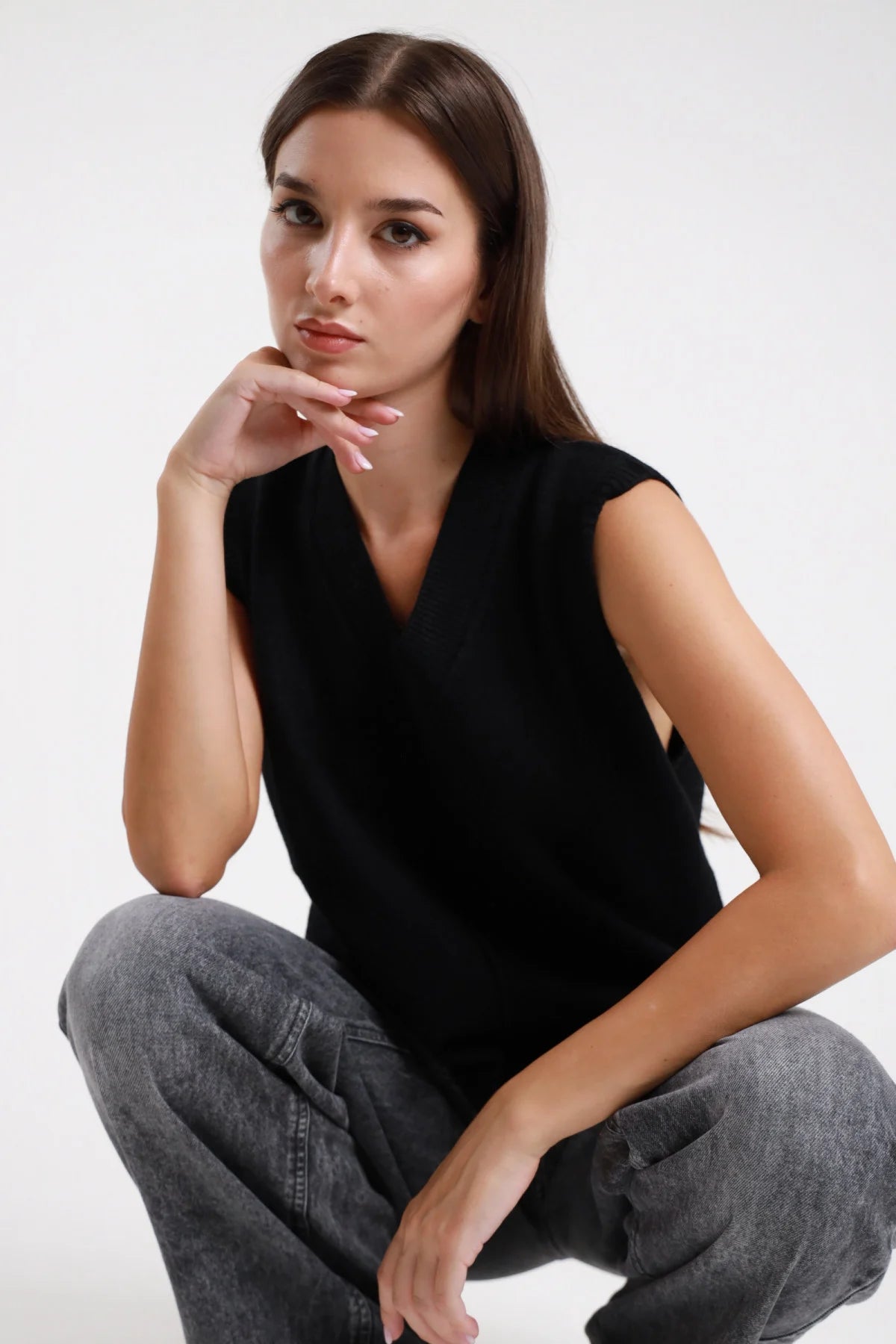 Gilet scollo V nero in maglia - modella seduta, vista frontale