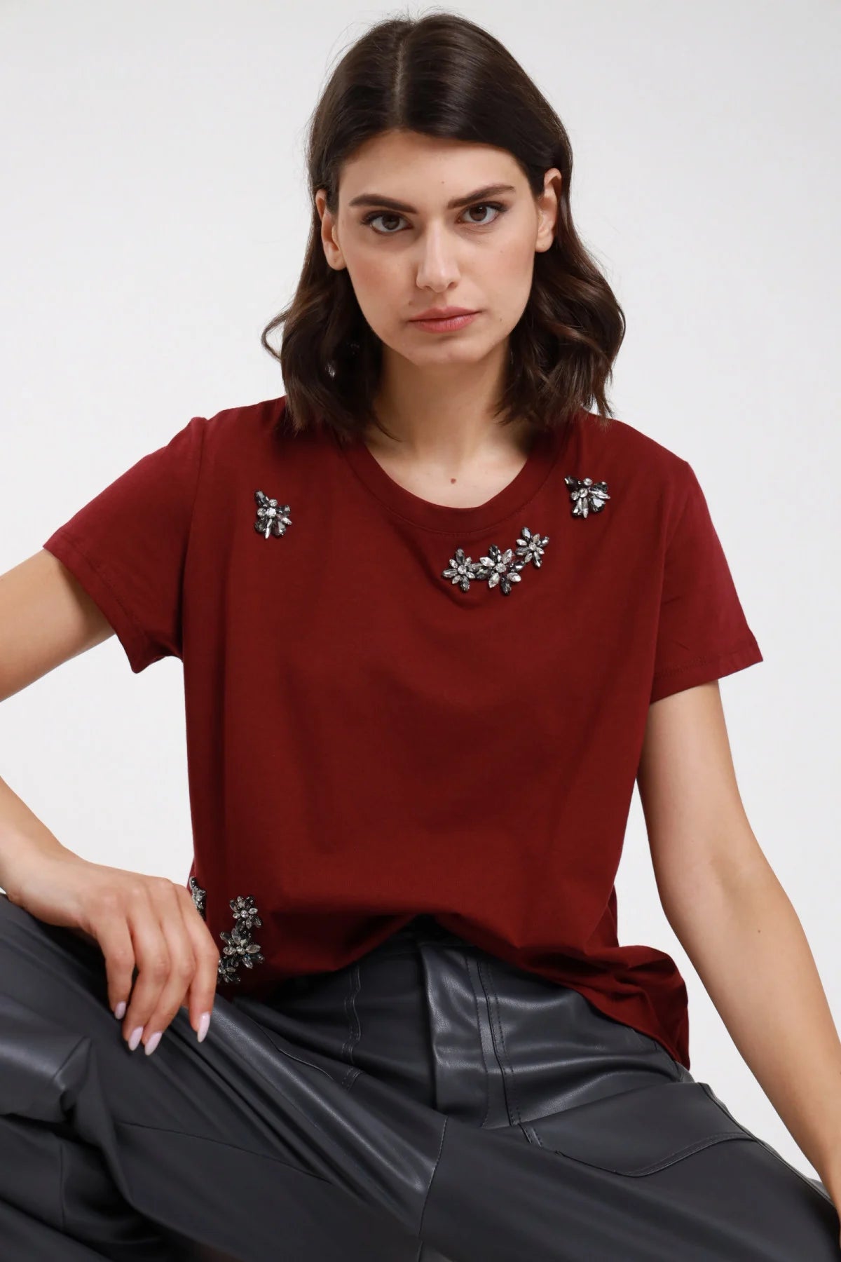 T-shirt strass bordeaux donna boxy applicazioni fiori strass - vista seduta con pantaloni in ecopelle grigi