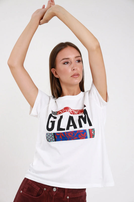T-shirt glam bianca frontale braccia alzate mani intrecciate stampa glam bold bande patchwork etnico floreale turchese - modella frontale braccia alzate mani intrecciate sguardo frontale pantaloni borgogna velluto capelli castani lisci