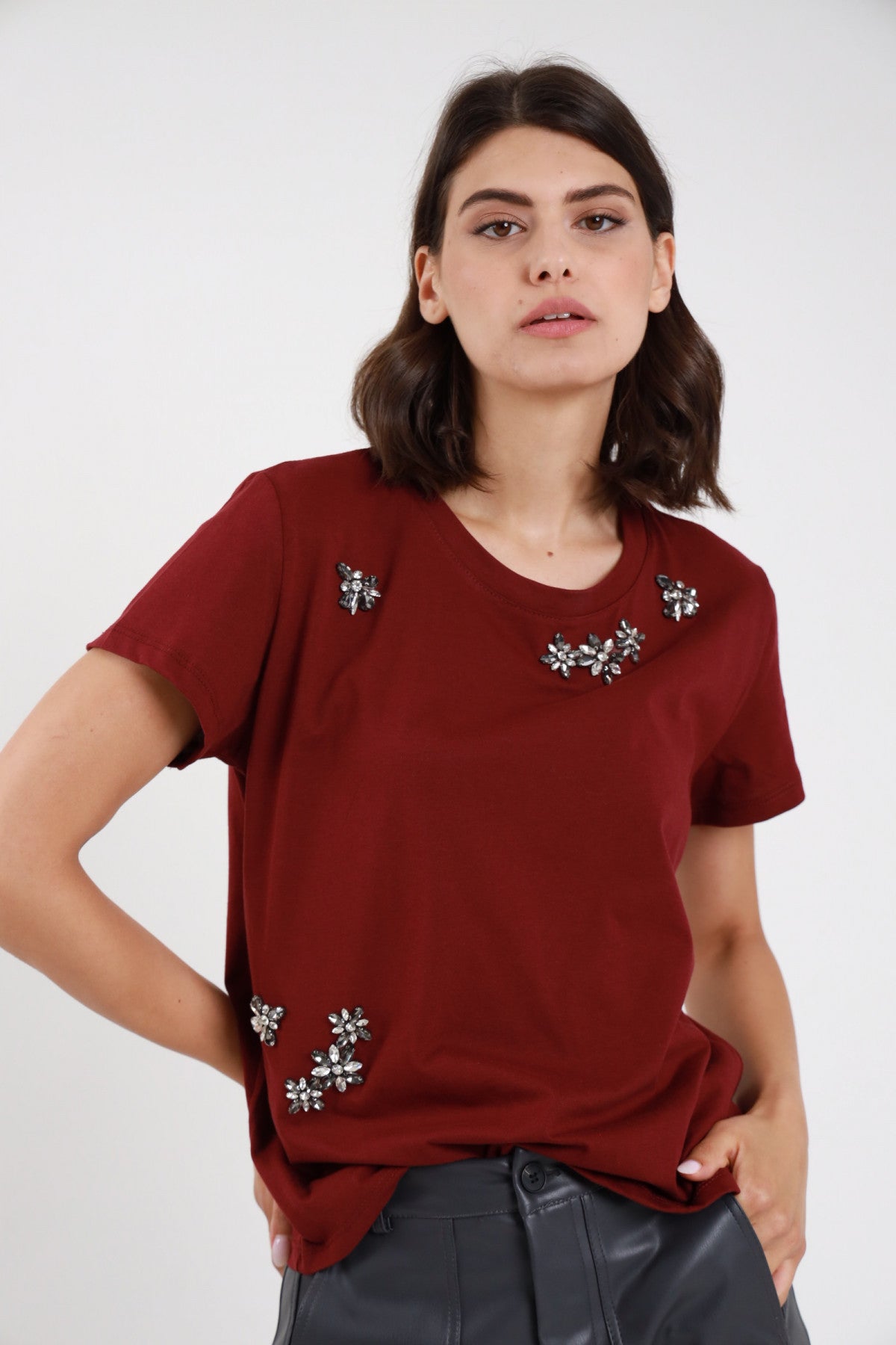 T-shirt strass bordeaux donna boxy con fiori strass sparsi sul davanti - vista frontale mani sui fianchi con pantaloni in ecopelle grigi