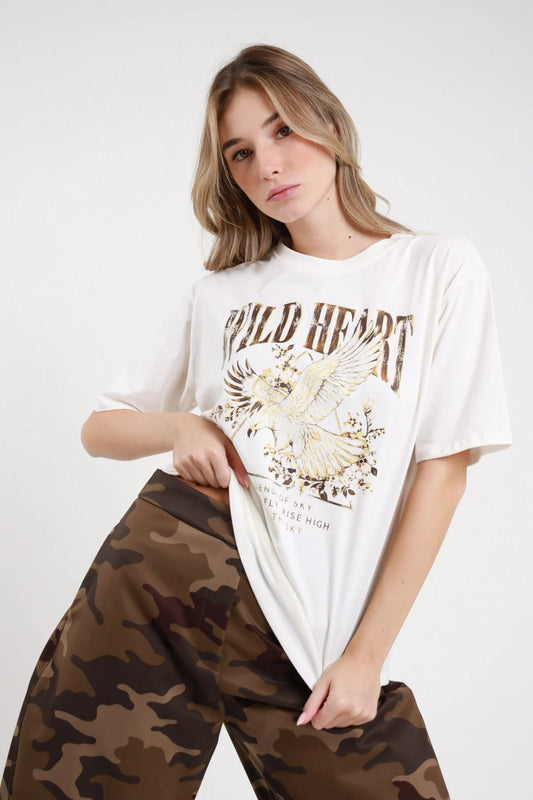 T-shirt Wild Heart Susy Mix Pre-Fall bianco panna 100% cotone stampa frontale Wild Heart aquila dorata fiori Born to Fly Rule the Sky girocollo manica corta oversize relaxed busto 3/4 mano vita sguardo frontale - modella busto 3/4 mano vita capelli biondi mossi sfondo bianco pantaloni mimetico marrone abbinati