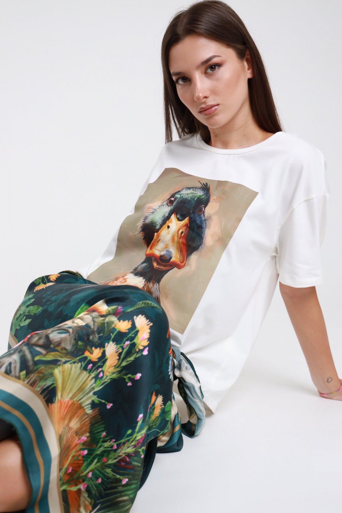 T-shirt bianca stampa germano reale donna Susy Mix – oversize vista seduta con gonna pareo fantasia