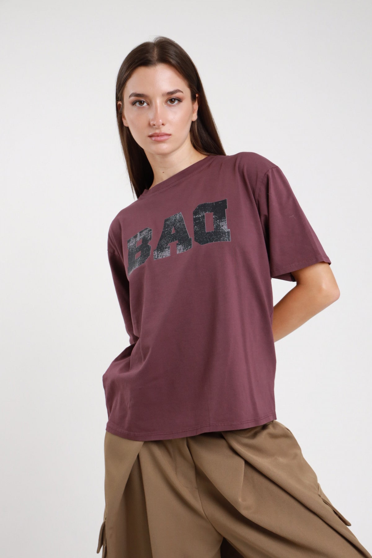 T-shirt Bad bordeaux prugna donna boxy oversize con stampa grafica college vintage - vista tre quarti con gonna cargo kaki