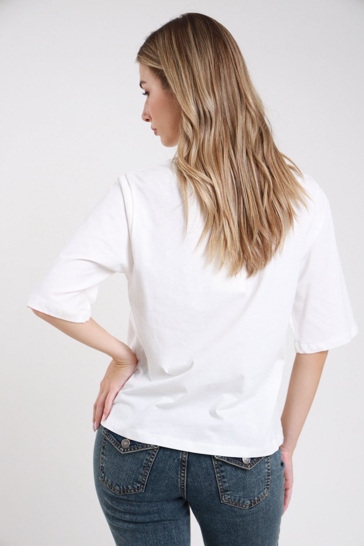 T-shirt bianca oversize con cravatta maglia righe bordeaux blu elettrico colletto raso cioccolato girocollo corpo boxy mani vita - modella frontale intera mani vita sguardo frontale jeans moro capelli castani raccolti corti