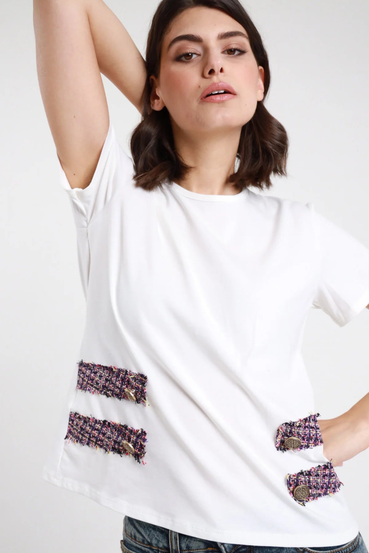 T-shirt tweed e bottoni bianca donna boxy girocollo maniche corte - dettaglio tasche tweed rosa viola nero con bottoni dorati metallo brunito braccio alzato