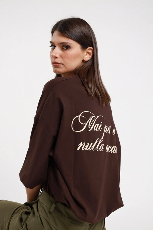 T-shirt over Mai per caso nulla accade Susy Mix Pre-Fall marrone cioccolato 100% cotone scritta corsivo panna retro 3/4 laterale sguardo camera - modella 3/4 laterale sguardo camera capelli scuri lisci sfondo bianco scritta corsivo retro parzialmente visibile pantaloni cargo verde militare abbinati