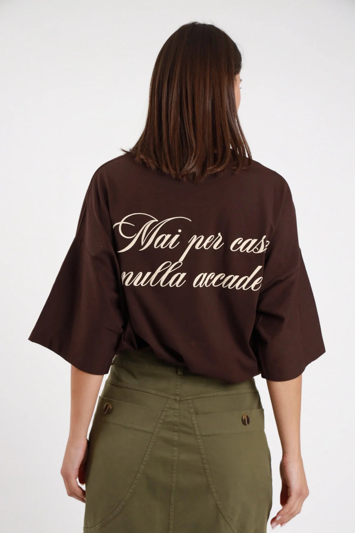 T-shirt over Mai per caso nulla accade Susy Mix Pre-Fall marrone cioccolato scritta corsivo panna Mai per caso nulla accade retro completo ben visibile posteriore intera - modella posteriore intera capelli scuri lisci sfondo bianco scritta corsivo retro completa leggibile pantaloni cargo verde militare abbinati