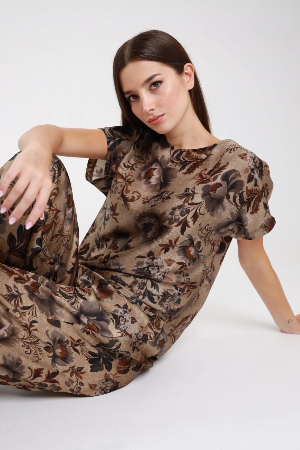 Blusa fantasia floreale barocco taupe beige seduta intera sul pavimento corpo boxy oversize gonna coordinata - modella seduta sul pavimento tre quarti sguardo laterale alto blusa gonna coordinata stesso tessuto capelli castani