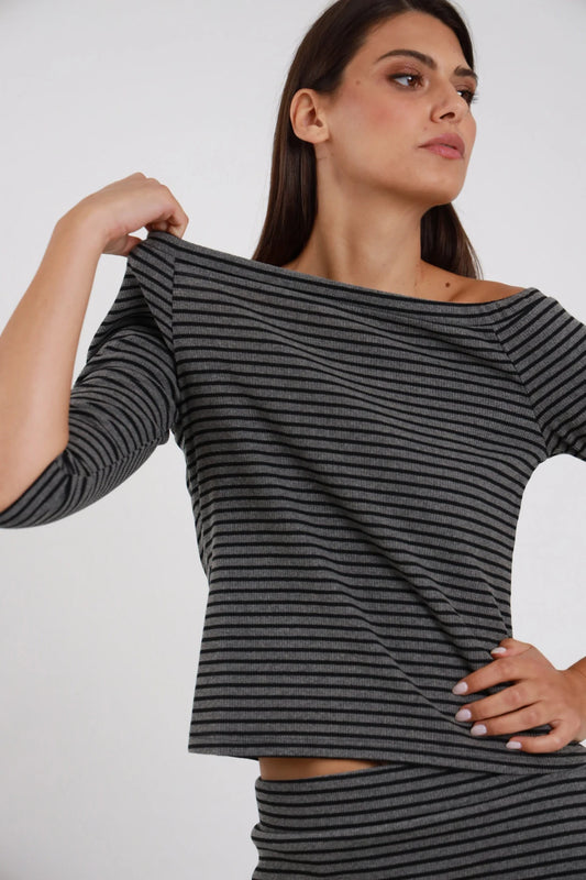 Top Righe Lurex grigio antracite nero 48% cotone scollo barchetta ampio off-shoulder manica 3/4 silhouette crop semi-aderente - modella busto 3/4 frontale posa mano tira colletto barchetta lateralmente sguardo laterale alto capelli castani lisci sfondo bianco gonna coordinata righe grigie