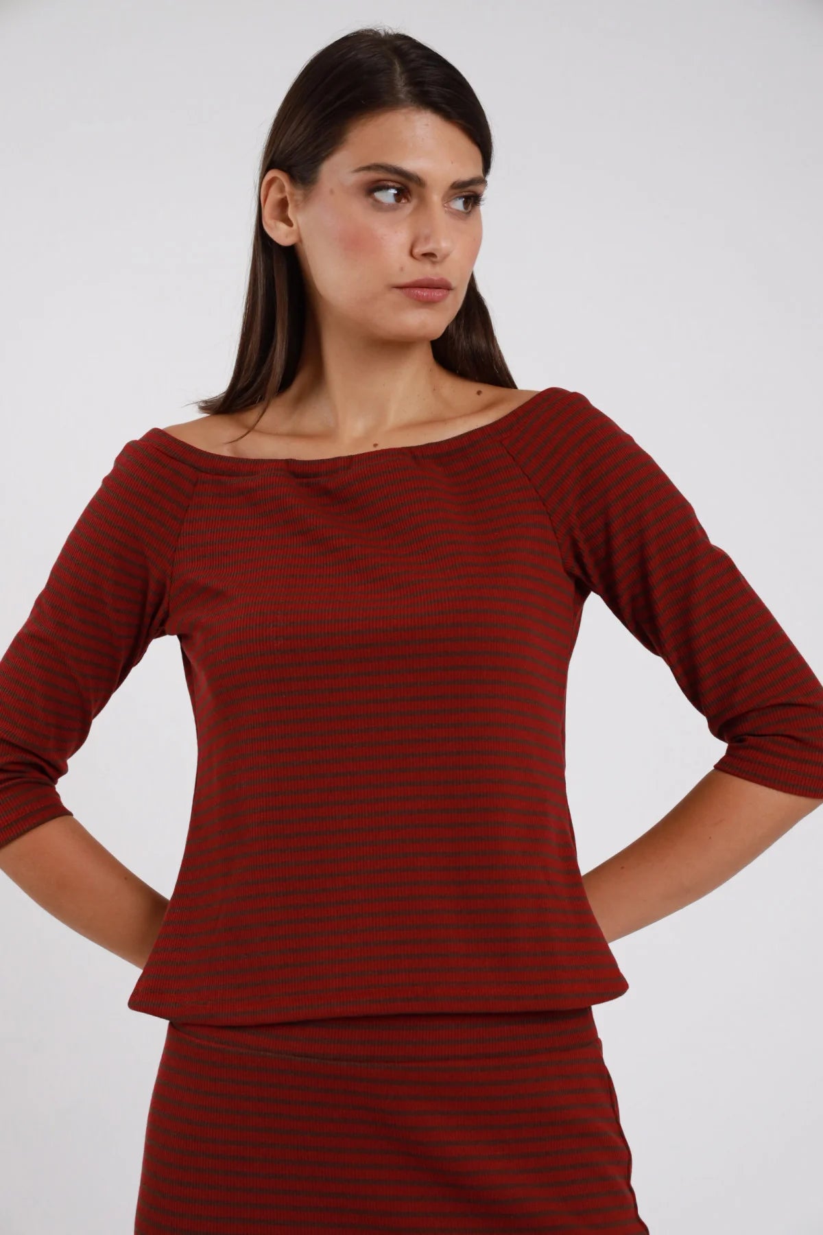 Top Righe Lurex bordeaux rosso nero 48% cotone scollo barchetta ampio manica 3/4 silhouette crop semi-aderente - modella busto frontale posa mani fianchi dietro sguardo laterale capelli castani lisci sfondo bianco gonna coordinata righe bordeaux rosso