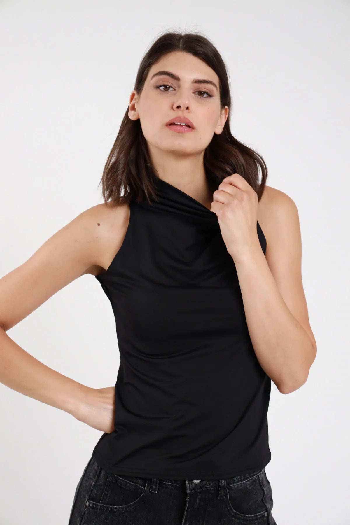 Top tactel nero donna collo alto arricciato drappeggio asimmetrico schiena halter aderente - vista frontale mano al collo con jeans neri