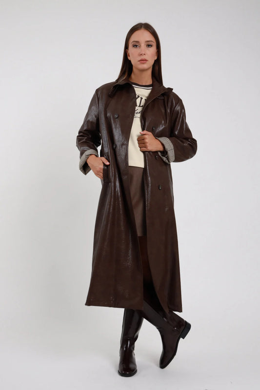 Trench Ecopelle marrone cioccolato scuro verniciata laccata crinkle colletto camicia doppiopetto bottoni bruniti tasche frontali applicate polsino risvolto check tartan lunghezza maxi midi frontale intera posa statica mano colletto aperta - modella frontale intera posa statica mano colletto sguardo camera capelli castani lisci sfondo bianco felpa panna brooklyn minigonna marrone stivali neri alti ginocchio piatto