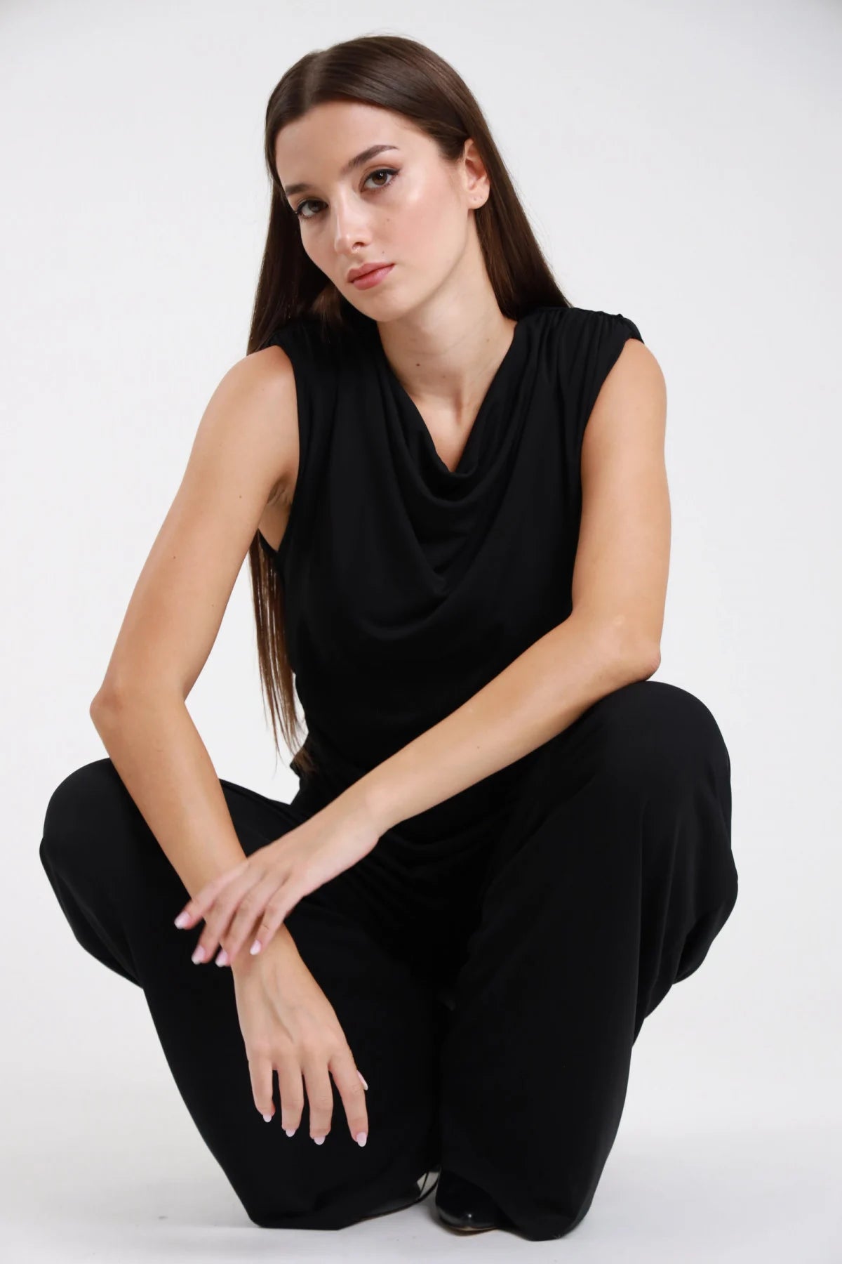 Tuta intera nera con scollo a cascata drappeggiato - modella seduta